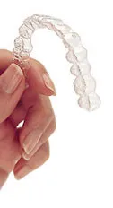 Hand holding a clear Invisalign aligner