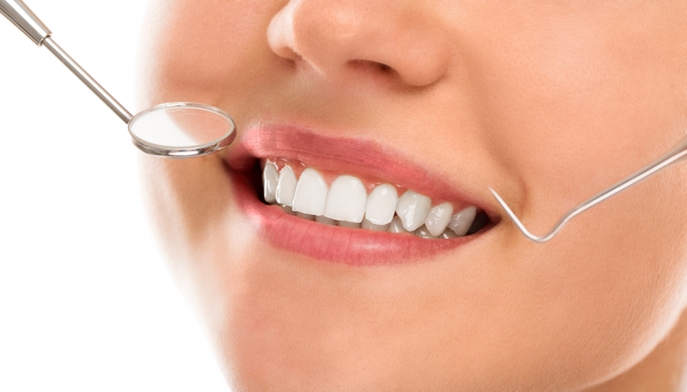 Dental mirror and probe held near a bright smile