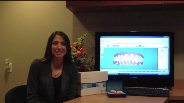 Woman beside a computer screen showing a 3D Invisalign treatment plan