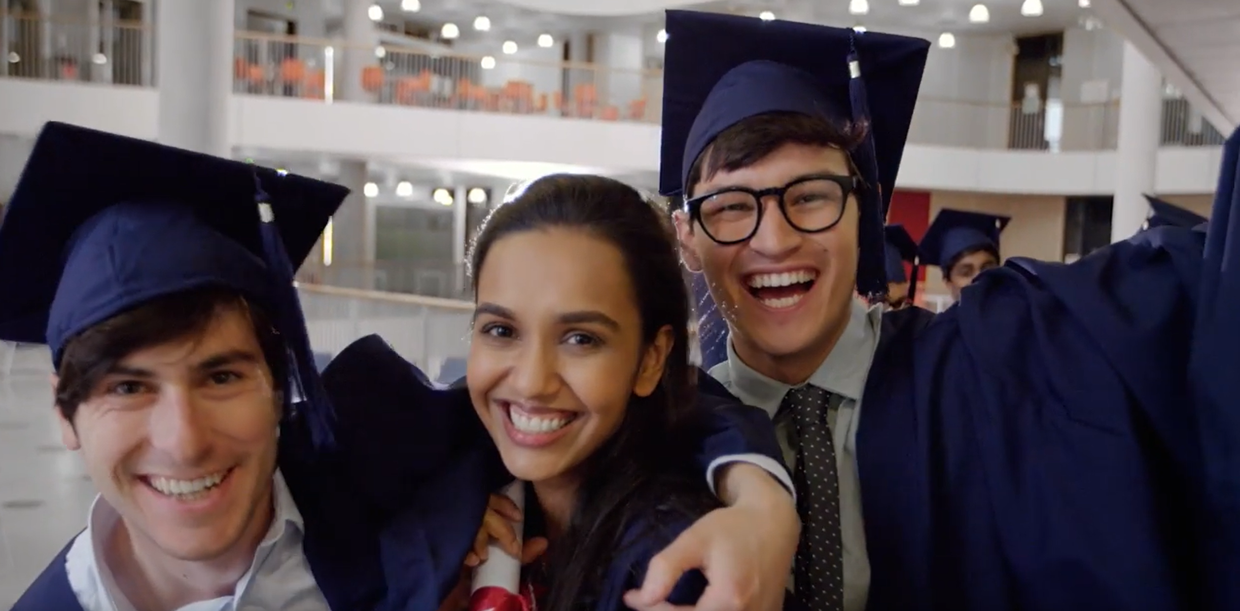 Smiling graduates in caps and gowns taking a selfie