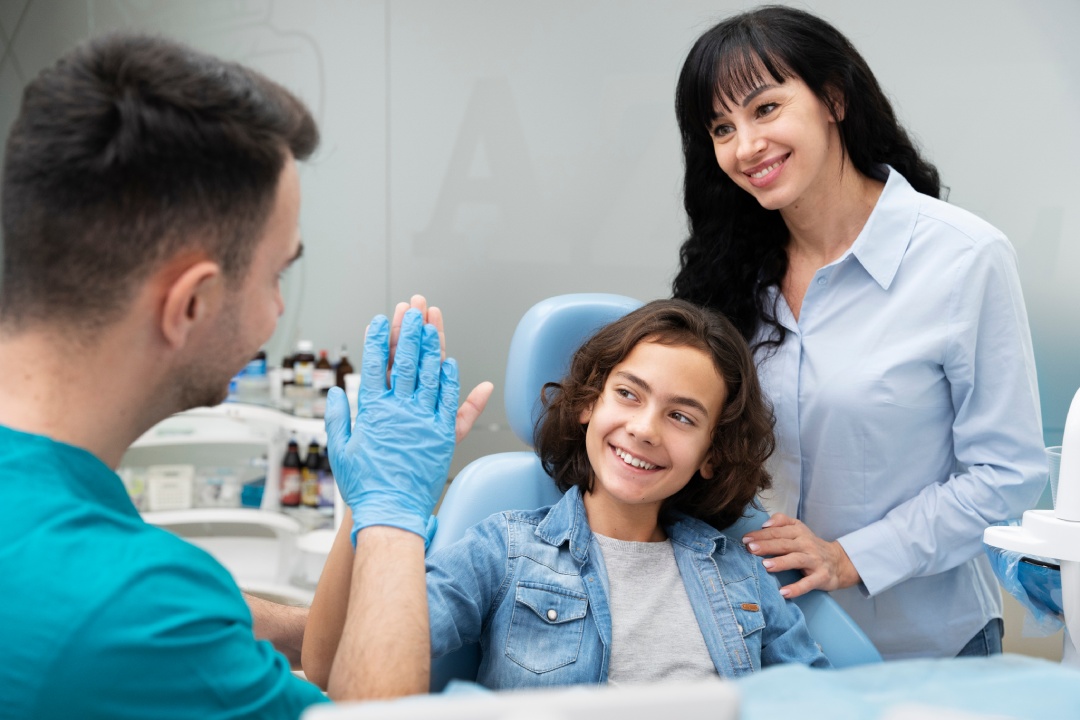 Orthodontist and assistant greeting a smiling young woman in the treatment chair