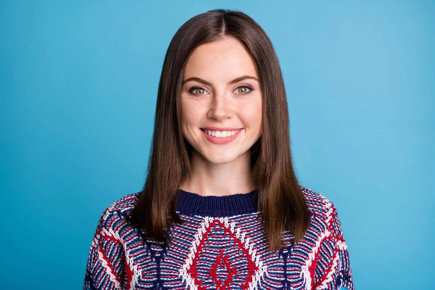 Smiling young woman with long brown hair against a blue background