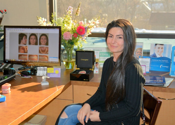 Woman seated at a desk with smile photos on the computer screen