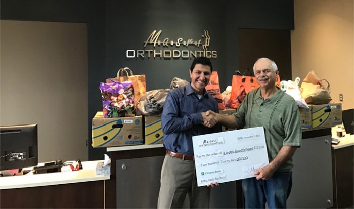 Two men holding an oversized check in the Masri Orthodontics office