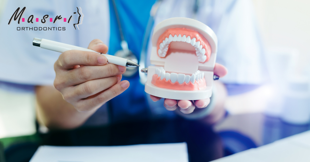 Masri Orthodontics team member pointing to a dental model with braces