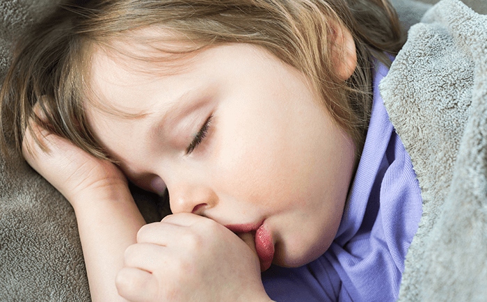 Young child sleeping while sucking a thumb